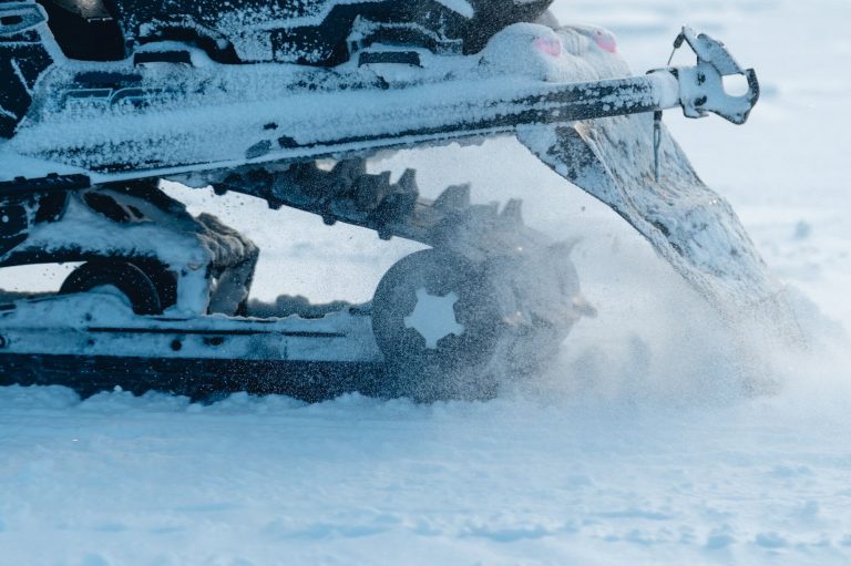 Closeup shot of the snowmobile wheels while splashing snow around