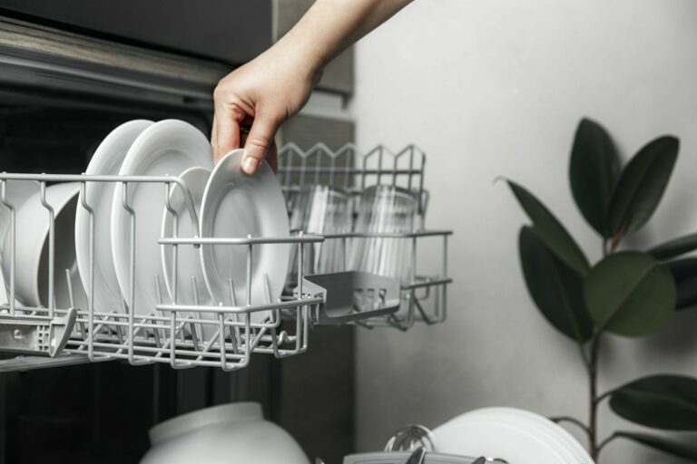 Open dishwasher with clean cutlery, glasses, dishes inside in the home kitchen